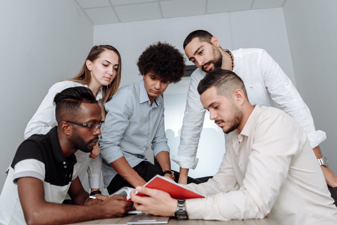 Small team collaborating around a laptop with team chat interface — affordable Slack alternatives for small businesses