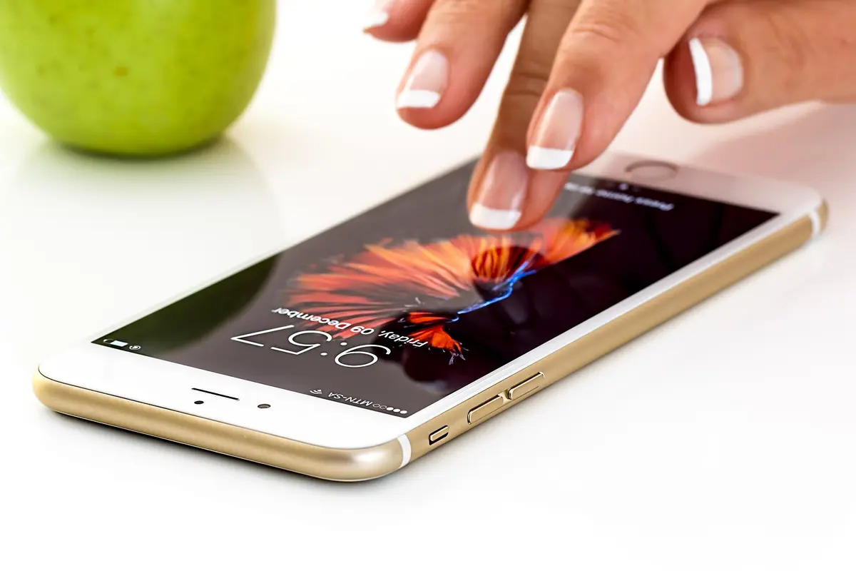 A hand tapping the screen of a smartphone lying on a table